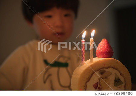 誕生日ケーキと男の子 ケーキのキャンドルを消す子供の写真素材