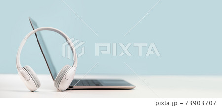 Laptop with headphones on white desk Laptop with headphones on white desk 73903707