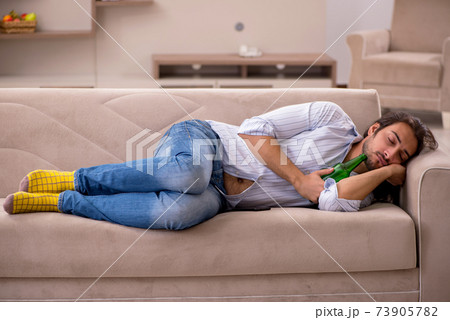 Young man drinking alcohol at home Young man drinking alcohol at home 73905782