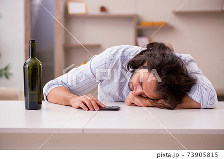 Young man drinking alcohol at home Young man drinking alcohol at home 73905815