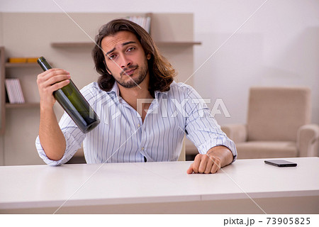 Young man drinking alcohol at home Young man drinking alcohol at home 73905825