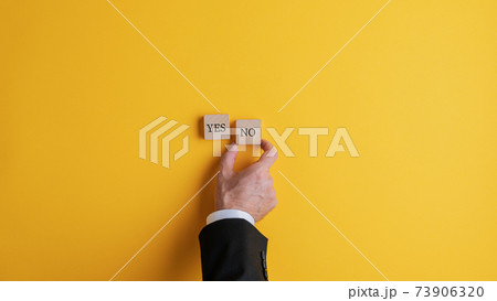 Businessman placing two wooden blocks with Yes and No words Businessman placing two wooden blocks with Yes and No words 73906320