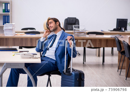 Young male employee preparing for trip in the office Young male employee preparing for trip in the office 73906798