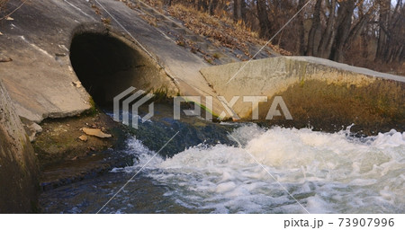 Large sewage tunnel with filth flowing out 73907996