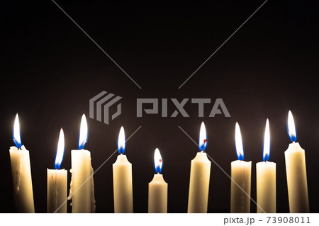 Candles glowing against dark background Candles glowing against dark background 73908011