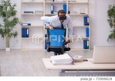 Young male employee wearing virtual glasses at workplace 73908628