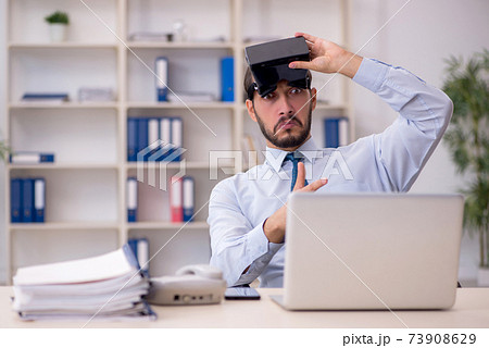 Young male employee wearing virtual glasses at workplace Young male employee wearing virtual glasses at workplace 73908629