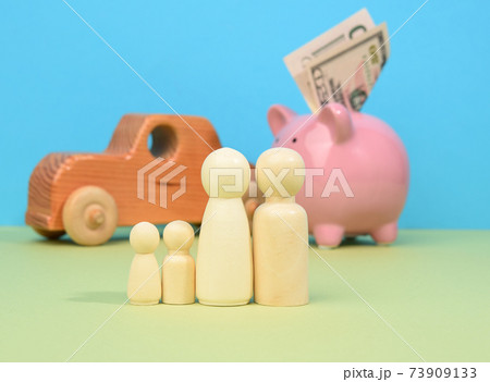 wooden little men family stands on the background of piggy bank pig and wooden car 73909133