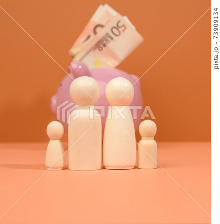 family of wooden figures on the background of a pink piggy bank 73909134