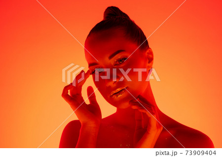 Handsome woman's portrait isolated on orange gradient studio background in neon light, monochrome 73909404