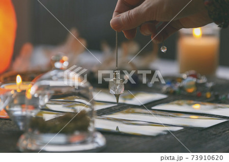 Hand with pendulum over tarot cards Hand with pendulum over tarot cards 73910620