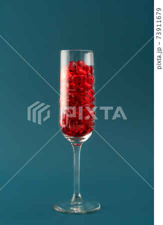 Beautiful card with champagne glass filled with transparent red hearts on dark aqua backdrop. Love and celebration concept. Great design for any purposes. 73911679