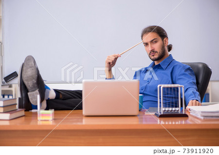 Young male teacher physicist sitting in the classroom Young male teacher physicist sitting in the classroom 73911920