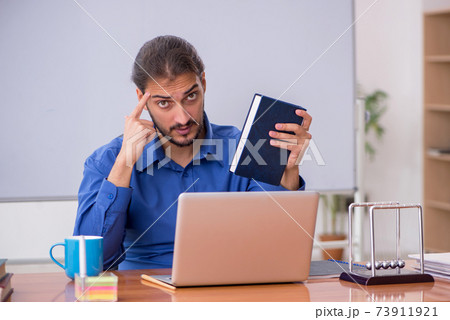 Young male teacher physicist sitting in the classroom 73911921