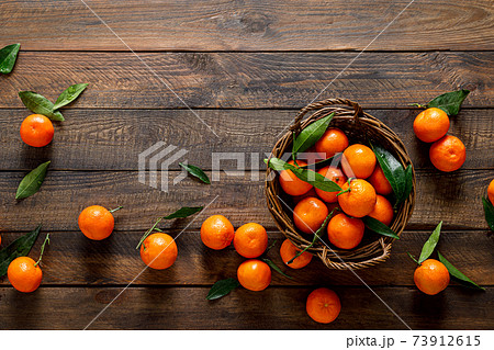 Tangerines, fresh mandarin oranges, clementines with leaves on wooden background. Top view, copy space Tangerines, fresh mandarin oranges, clementines with leaves on wooden background. Top view, copy space 73912615