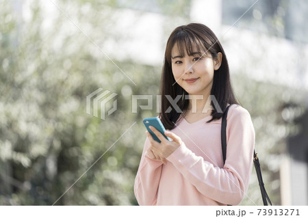 スマホを持ったカメラ目線の若い女性の写真素材