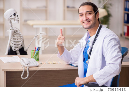 Young male doctor and skeleton patient in the clinic 73913418