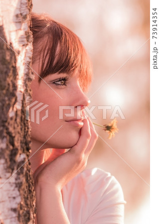 Beautiful girl with flower dreaming at nature tree 73914354