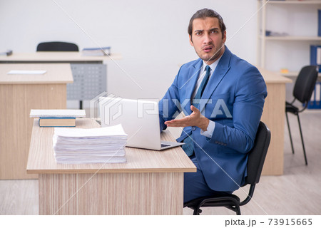 Young male employee and too much work in the office 73915665
