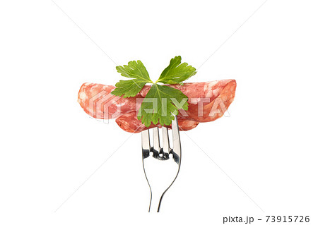 Three thin slices of cooked smoked sausage with parsley leaf. 73915726