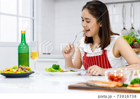 Happy Asian woman enjoy eating steak she make. Concept woman preparing meals at home. Happy Asian woman enjoy eating steak she make. Concept woman preparing meals at home. 73916738
