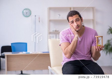 Young male patient waiting for doctor in time management concept Young male patient waiting for doctor in time management concept 73919478