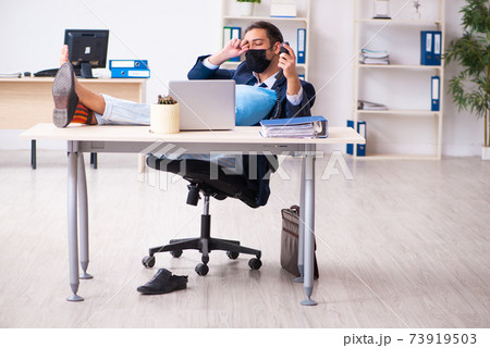 Young male employee during pandemic at workplace Young male employee during pandemic at workplace 73919503