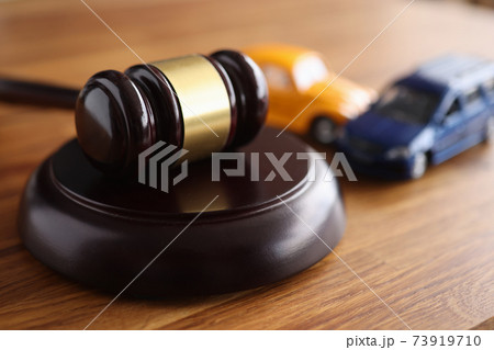 Judges wooden gavel lying on table near toy machines closeup 73919710