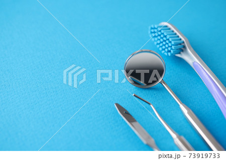 Dental instruments and toothbrush lying on blue background Dental instruments and toothbrush lying on blue background 73919733