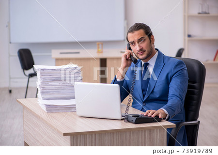 Young male employee and too much work in the office 73919789