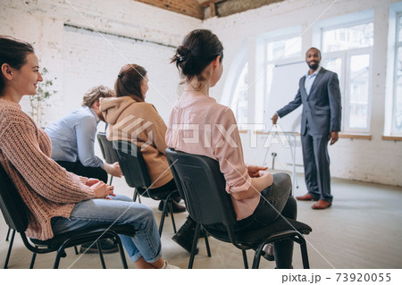 Male speaker giving presentation in hall at workshop. Audience or conference hall. Side view of unrecognized participants. Male speaker giving presentation in hall at workshop. Audience or conference hall. Side view of unrecognized participants. 73920055