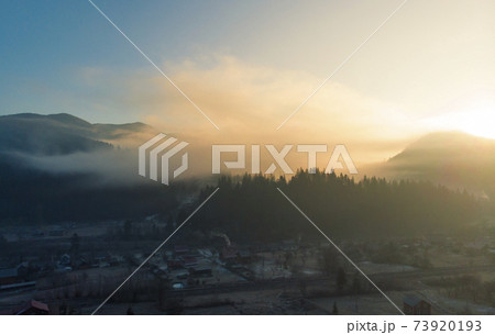 Mountains in the Morning. Majestic Sunrise in a Valley at Foggy Morning Mountains Landscape. Firs and Cozy Houses in Carpathians, Tatariv, Ukraine, Europe 73920193