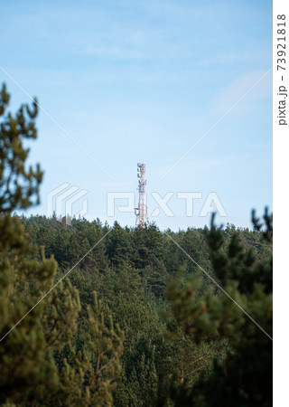 A telecommunications tower on top of forest hill with clear blue sky lots of copy space for advert text clean sharp colors and focus A telecommunications tower on top of forest hill with clear blue sky lots of copy space for advert text clean sharp colors and focus 73921818