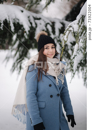 Pretty woman in blue coat walking in the woods on a winter snowy day. Beautiful woman posing to photographer 73922004