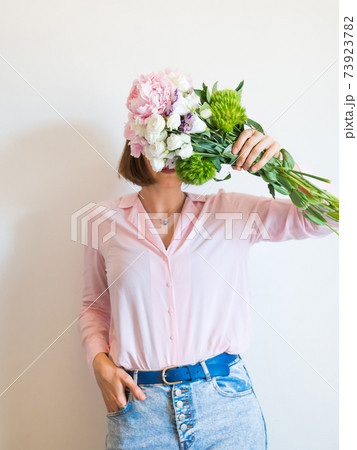 Young woman holding beautiful pink bouquet in front of her face Young woman holding beautiful pink bouquet in front of her face 73923782