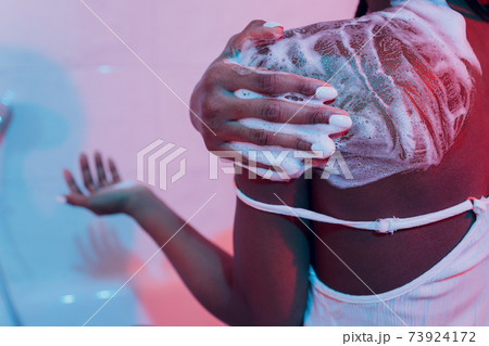 Pretty smiling black girl applying cream on her shoulder, body care concept. 73924172