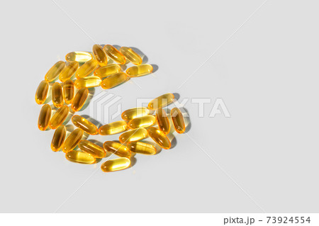 Yellow gelatin capsules on a gray background in the shape of the letter C. Food supplement, vitamin C Yellow gelatin capsules on a gray background in the shape of the letter C. Food supplement, vitamin C 73924554