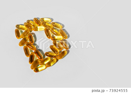 Yellow gelatin capsules on a gray background in the shape of the letter D. Food supplement, vitamin D, Yellow gelatin capsules on a gray background in the shape of the letter D. Food supplement, vitamin D, 73924555