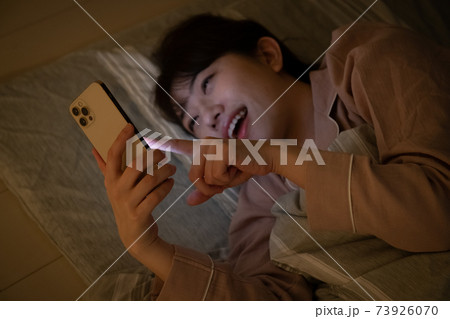 暗い部屋でスマホを見る女性 暗い部屋でスマホを見る女性 73926070