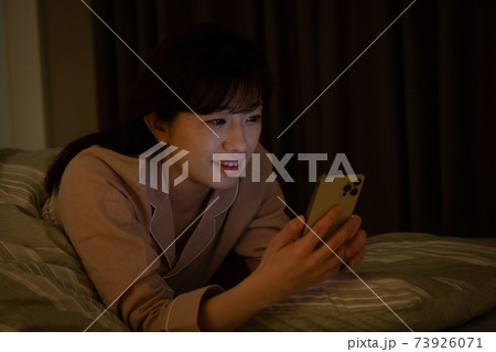 暗い部屋でスマホを見る女性 73926071