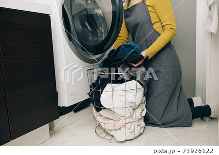 ドラム式洗濯乾燥機に洗濯物を出す・入れる女性の手元 73926122