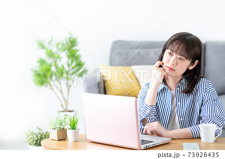 自宅のリビングルームでパソコンを見ながら悩む若い女性 自宅のリビングルームでパソコンを見ながら悩む若い女性 73926435
