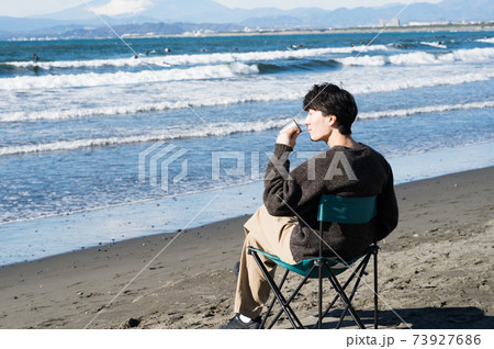 江ノ島の海を眺めながらコーヒを飲む男性 73927686