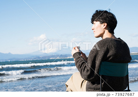 江ノ島の海を眺めながらコーヒを飲む男性 73927687
