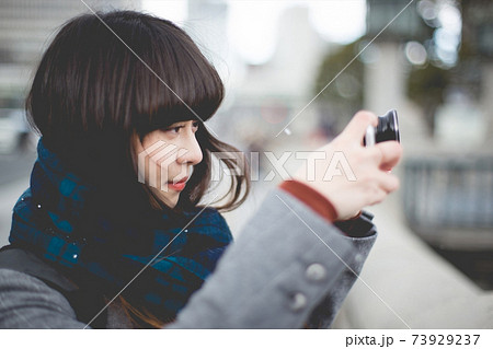 写真撮影　フィルムカメラを構えるマフラーを巻いた女性のアップ 73929237