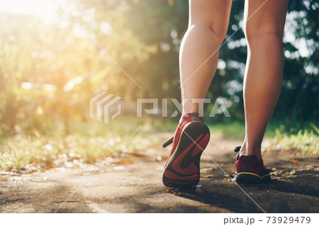 Woman wear running shoe on to walking and running on nature green background.Health exercise. Woman wear running shoe on to walking and running on nature green background.Health exercise. 73929479
