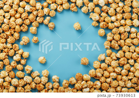 Popcorn is scattered on a blue background, in the form of a frame. 73930613