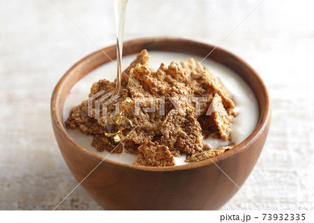 はちみつを注いでいる朝食のシリアル 73932335