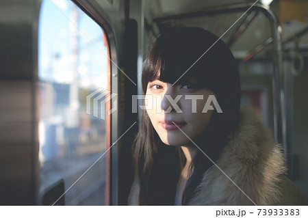 電車内　光と影　ファーコートを着ているロングヘアの女性 73933383
