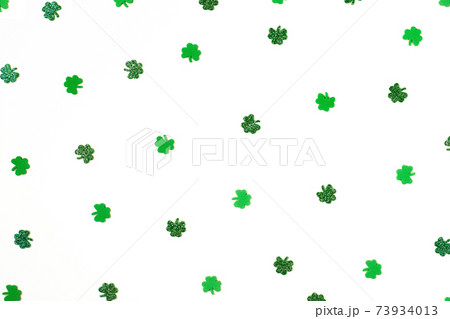 green shimmering shamrock confetti sparse on white background  73934013